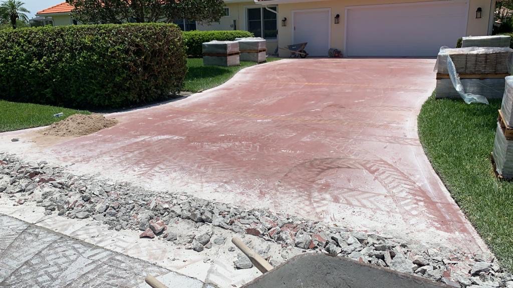 A driveway with pink concrete and gravel on it.