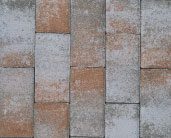 Close-up of a brick wall with alternating vertical rows of red and grey bricks, some of which have white speckles.