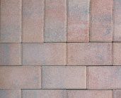 A close-up view of a brick wall with rectangular bricks arranged in a staggered pattern. The bricks are mostly light red with some greyish patches.