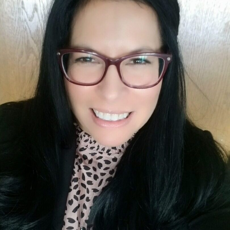 A woman with glasses and black hair wearing a leopard print scarf.